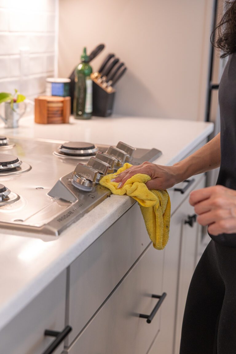 A Flash Brazilian Cleaning professional wiping down a kitchen cooktop